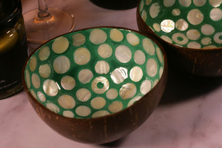 Coconut shell with green and white polka dot pattern on a pink surface