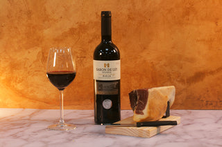 Bottle of Baron de Ley red wine with a glass and a piece of cured meat.  Luxury Gift